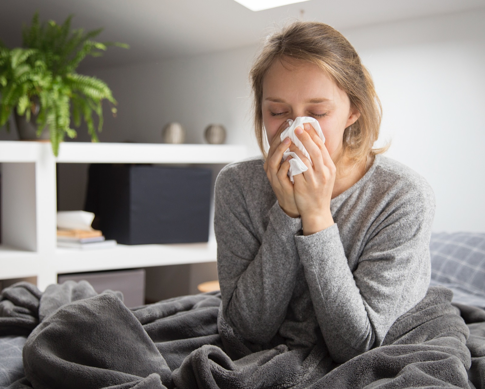 ragazza con l'influenza che si soffia il naso