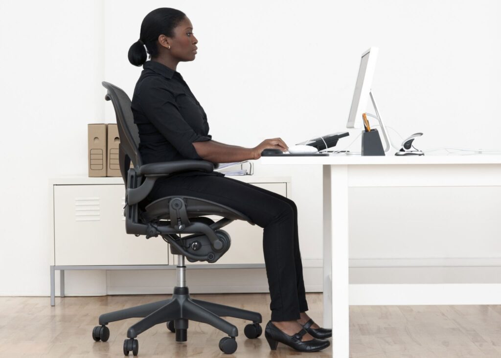 donna seduta correttamente alla scrivania 